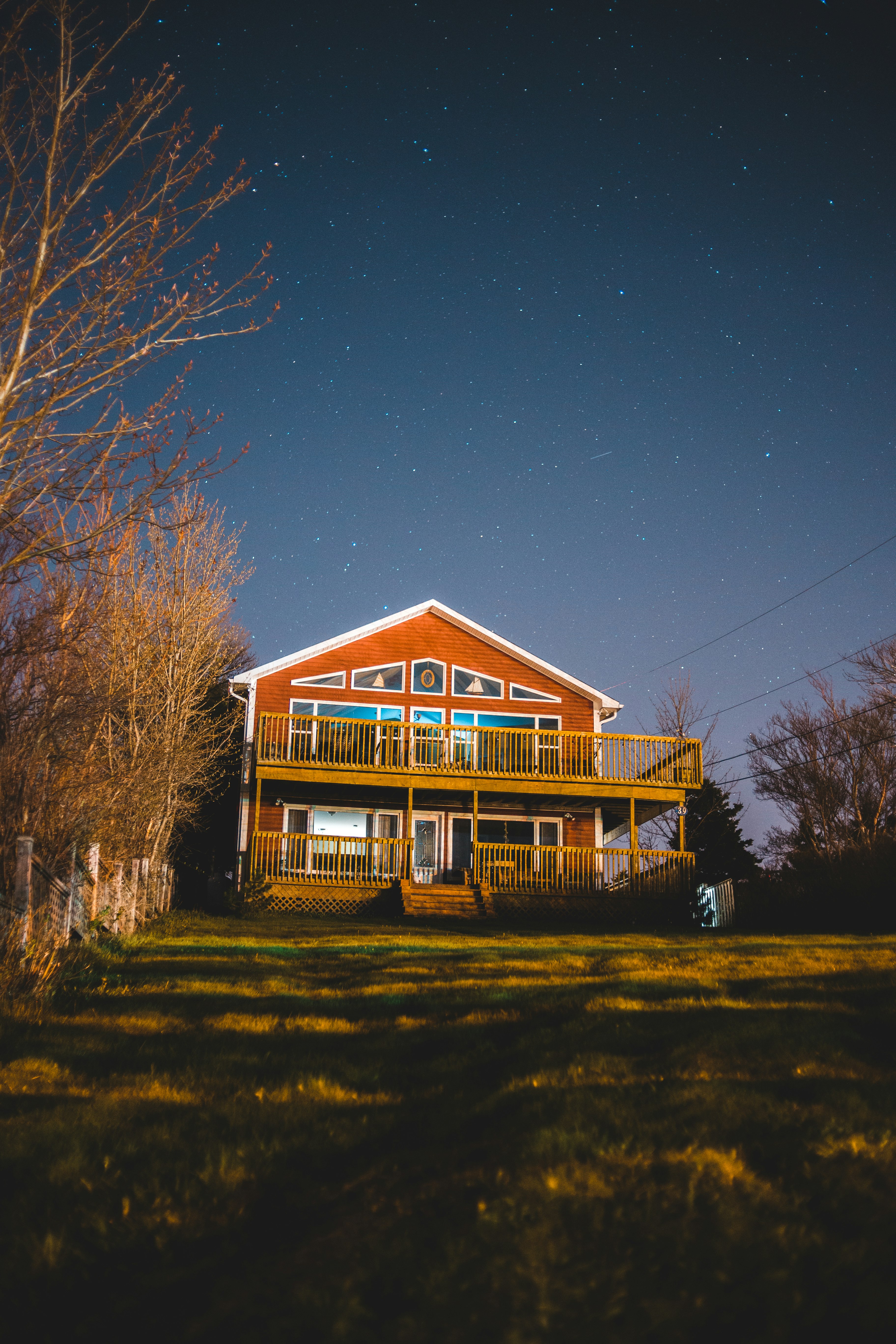 brown and white wooden house near bare trees under blue sky during night time